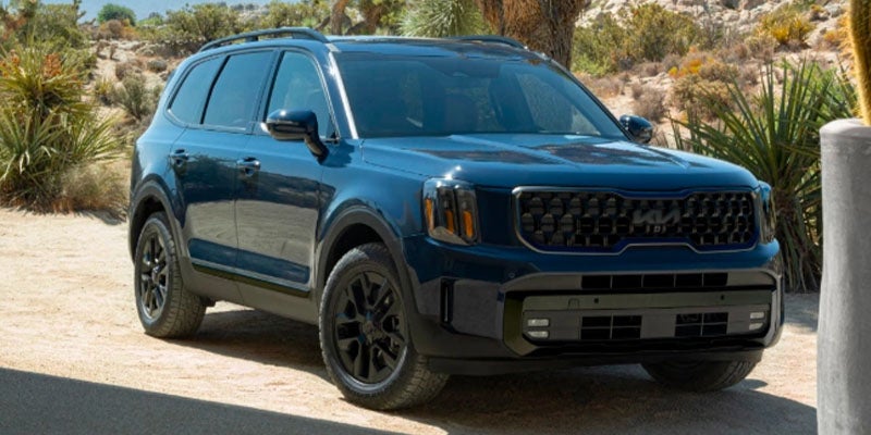 A dark blue Kia Telluride SUV parked in a desert landscape