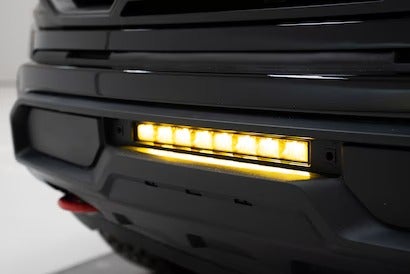A close-up of a truck's rear bumper with a yellow LED light bar