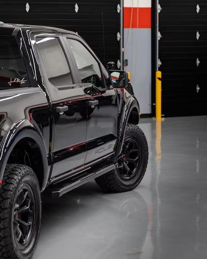 The side view of a black truck with red racing stripes