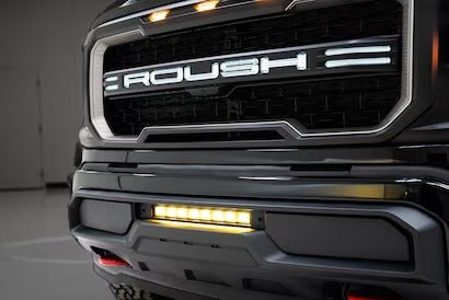 The front of a truck with a ROUSH grille and LED light bar