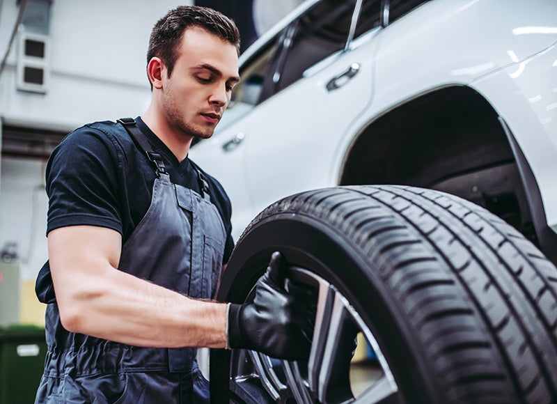 Mechanic installing tire on vehicle in auto repair shop